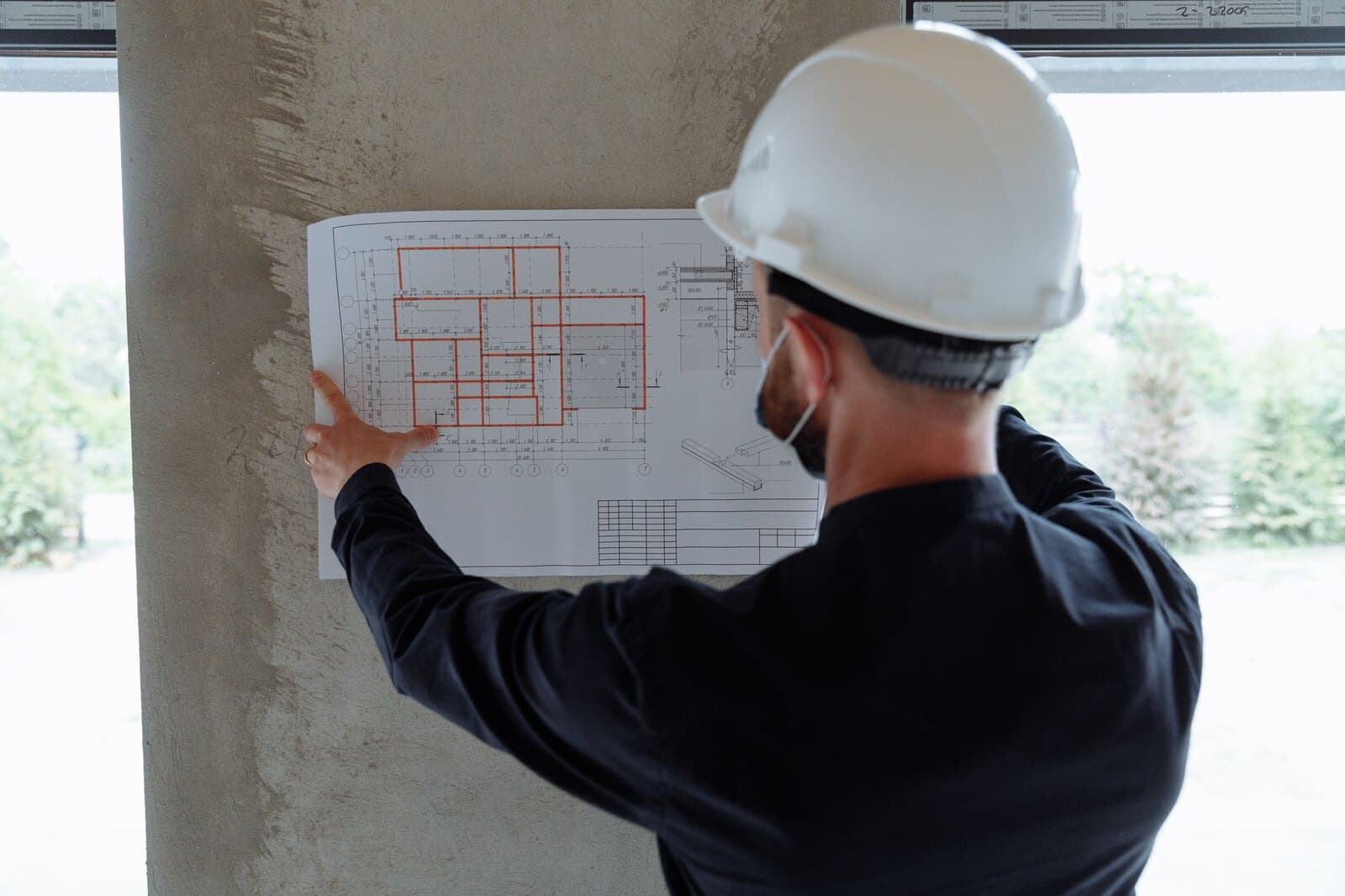 Engineer in a hard hat reviewing plans at an active construction site