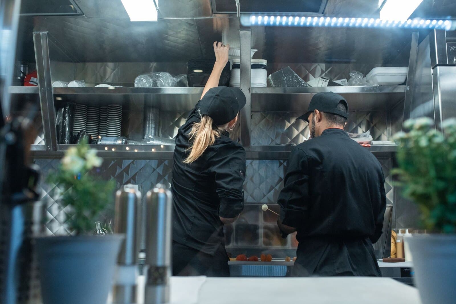 Chefs working beneath a stainless steel commercial kitchen hood