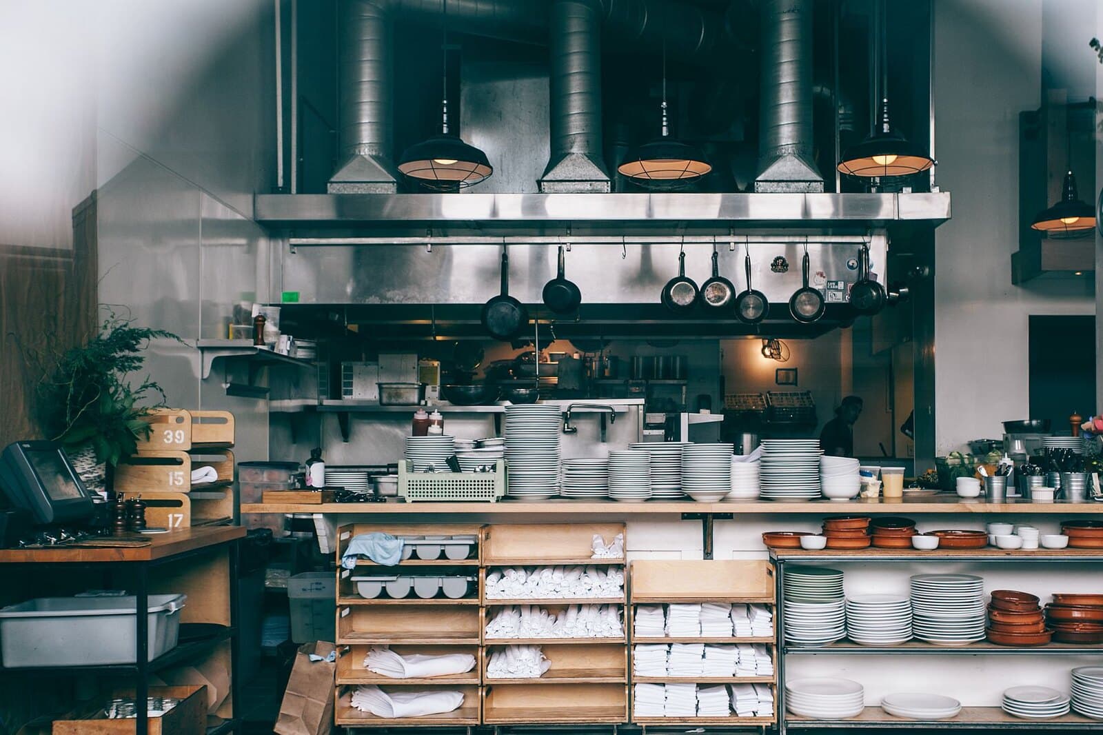 Clean restaurant kitchen with organized plates, utensils, and work surfaces