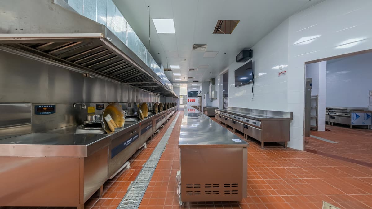Modern commercial kitchen interior with stainless steel appliances and tiled flooring